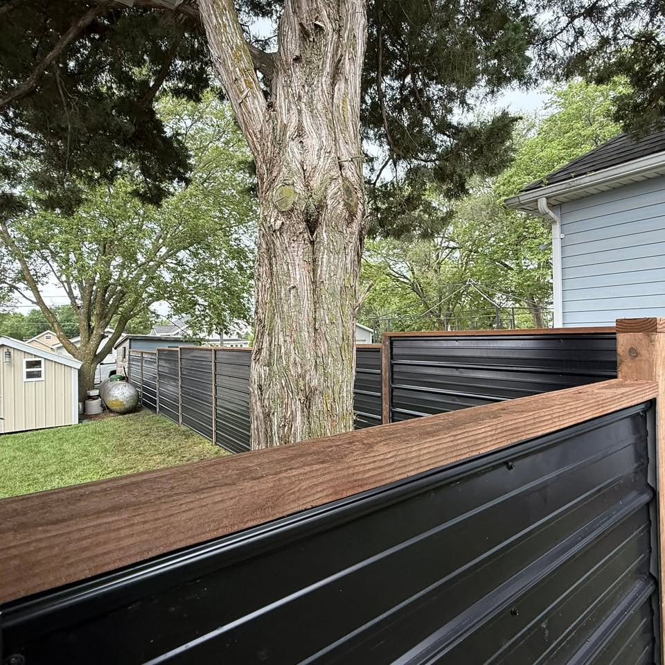 Corrugated black metal specialty fence with wood cap rail installed in Southeast Nebraska by KD Fencing